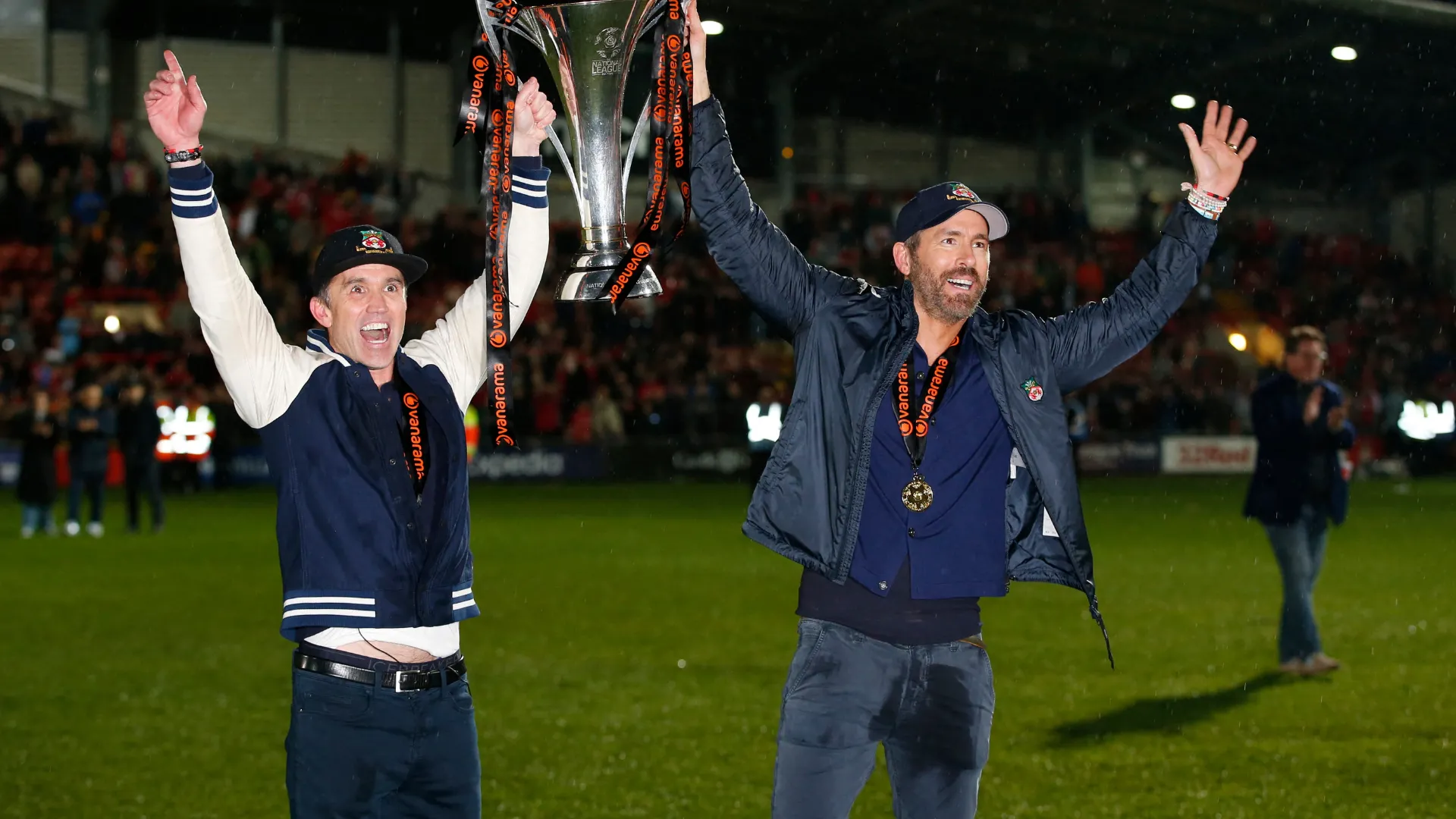 Ryan Reynolds và Rob McElhenney ăn mừng thành công của Wrexham trên khán đài.
